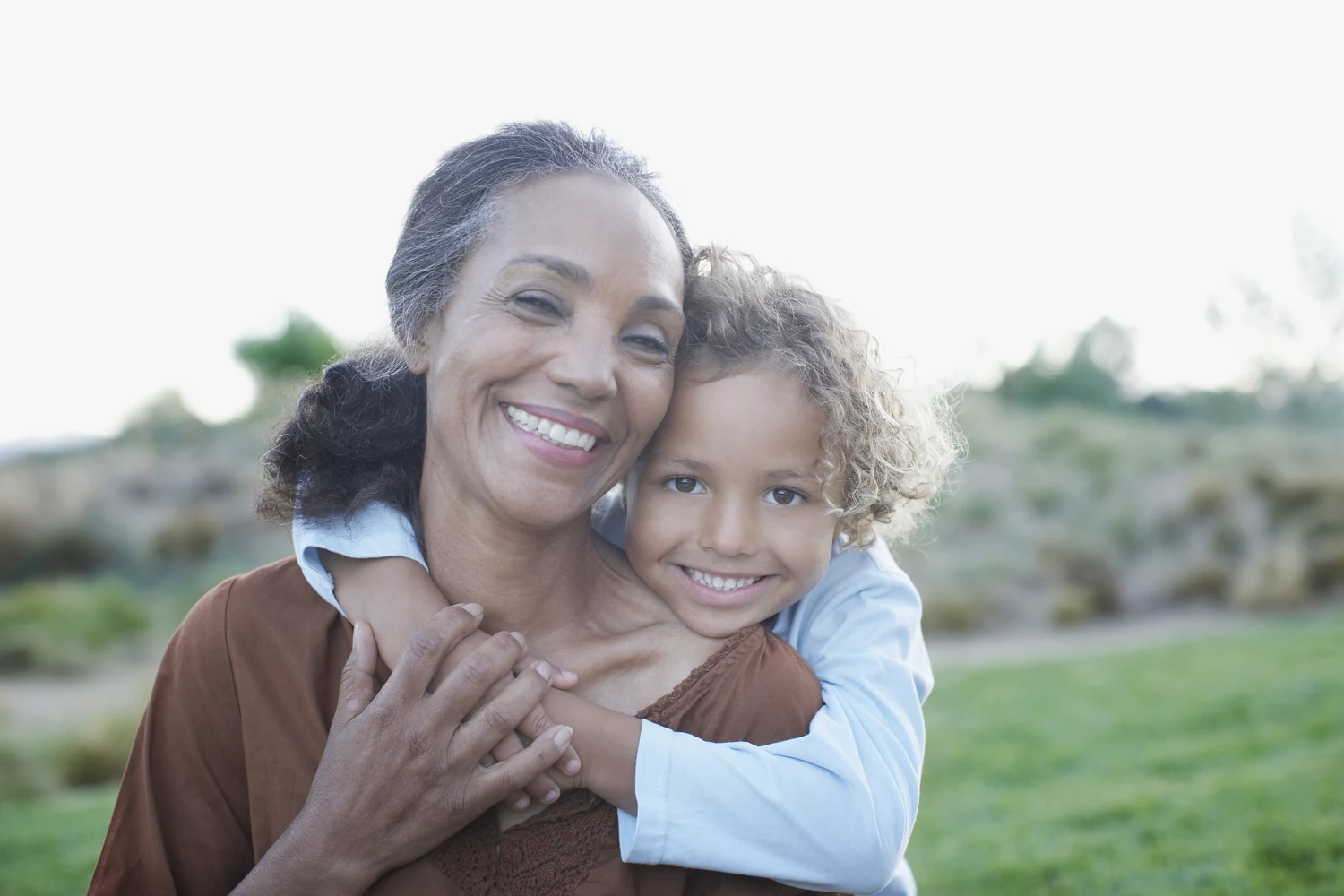 A grandmother embracing her granddaughter outdoors